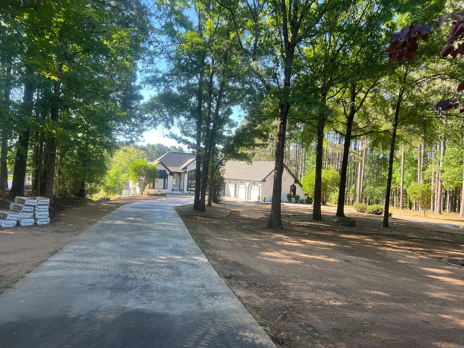 Freshly seeded lawn in Aiken, SC with an even layer of straw mulch covering bare soil on a residential property. Straw applied across a flat yard and gentle slope to protect seed from rain and surface runoff.